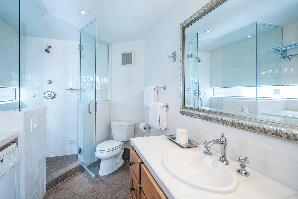 A contemporary bathroom with a glass shower enclosure, mirrored vanity, and sleek modern fixtures. The inviting atmosphere suggests a refreshing shower experience in a serene setting.